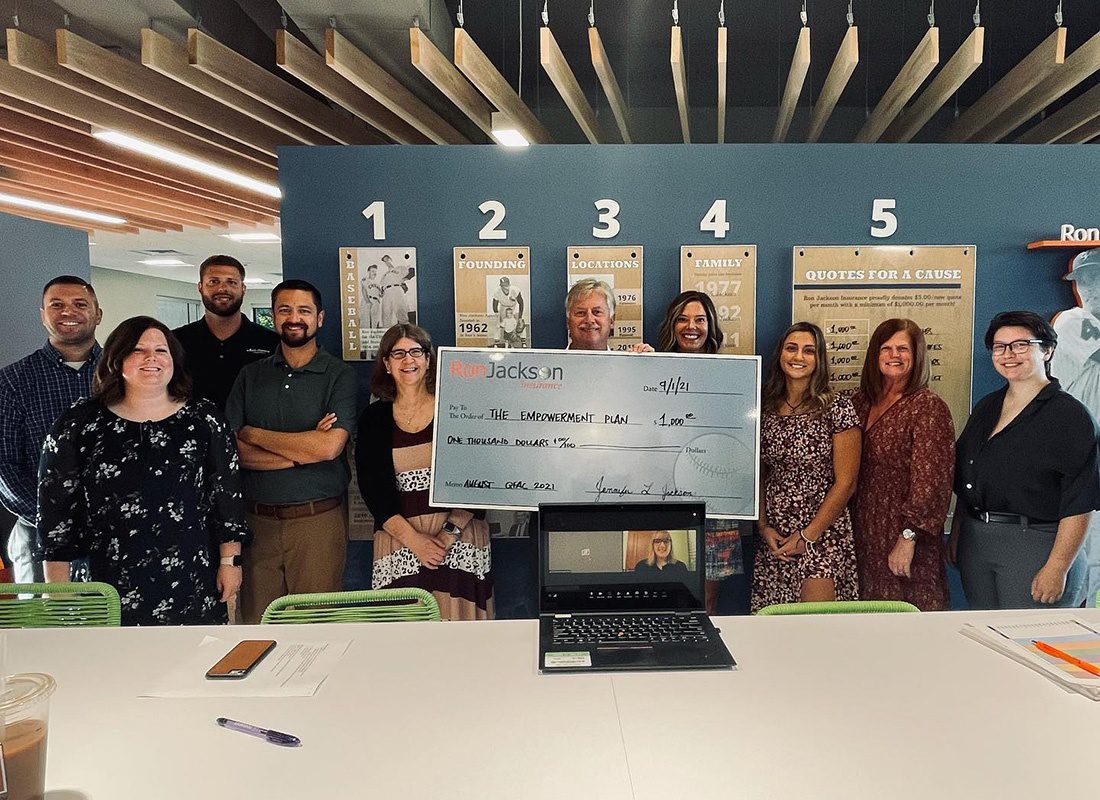 Quotes For A Cause - Smiling Portrait of the Ron Jackson Insurance Team Standing in the Office While Holding Up a Big Empowerment Plan Check